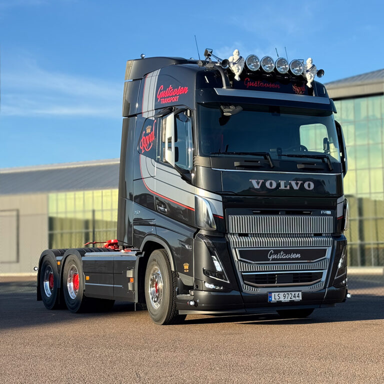 Sort Volvo lastebil med foliedekor i grått og rødt. Logo for Gustavsen Transport