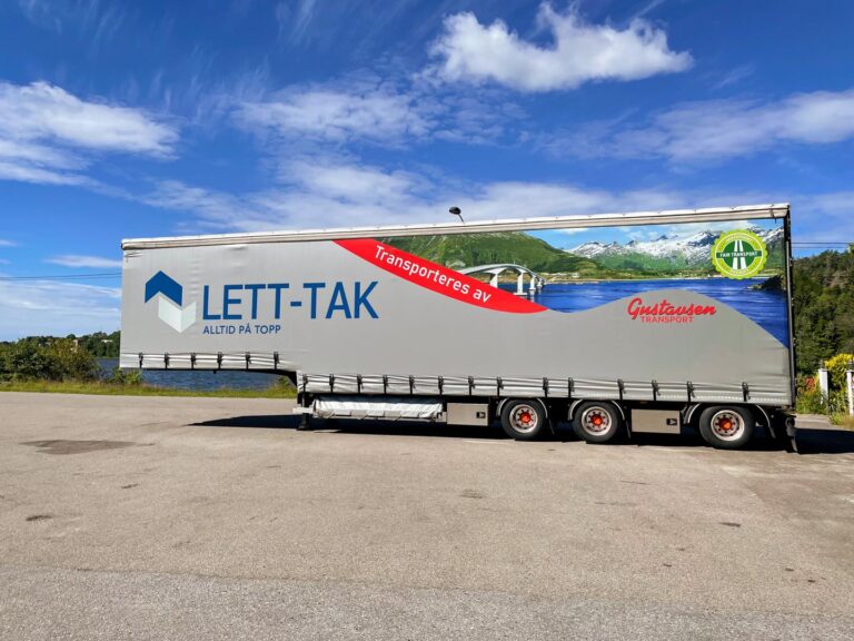 Lastebil med LETT-TAK og Gustavsens Transport-logo parkert på vei med fjell og fjord i bakgrunnen under blå himmel