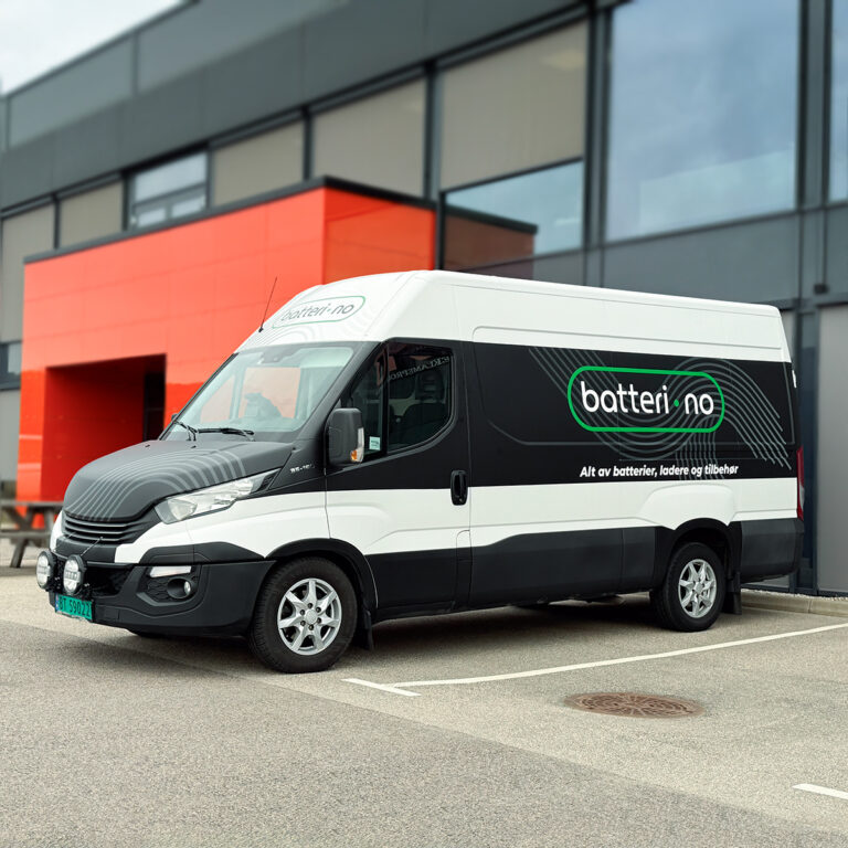Stor kassebil utenfor næringslokalene til UTD Reklameprodusenten - halvfoliert med sort bilfolie, grå detaljer og hvit og grønn logo for Batteri.no