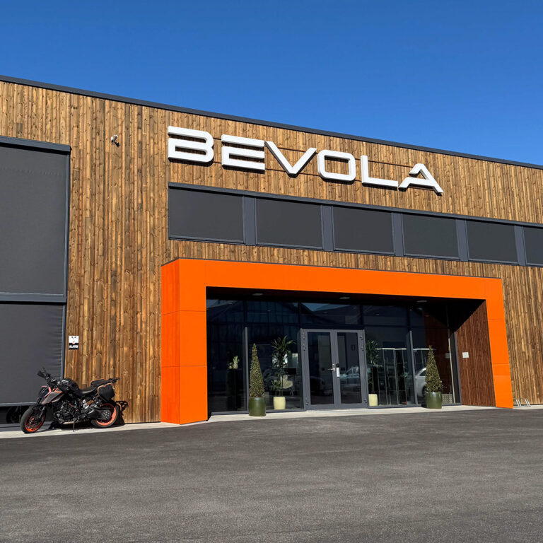 LED lysskilt utvendig på næringsbygg med oransje inngangsportal - Bevola, fasadeskilt