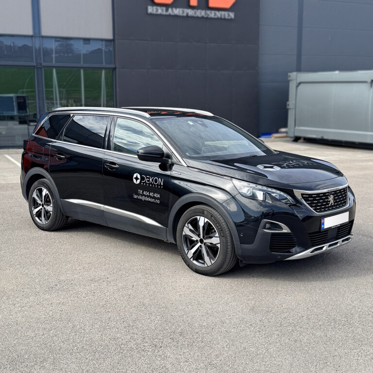 Sort Peugeot stasjonsvogn utenfor UTD Reklameprodusenten med utskåret folie og logo for Dekon Regnskap. Bilreklame