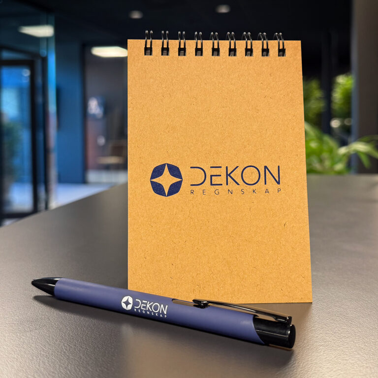 Profilartikler - notatblokk med spiralisert topp og resirkulert papp omslag med logo og reklamepenn med logo - Dekon Regnskap
