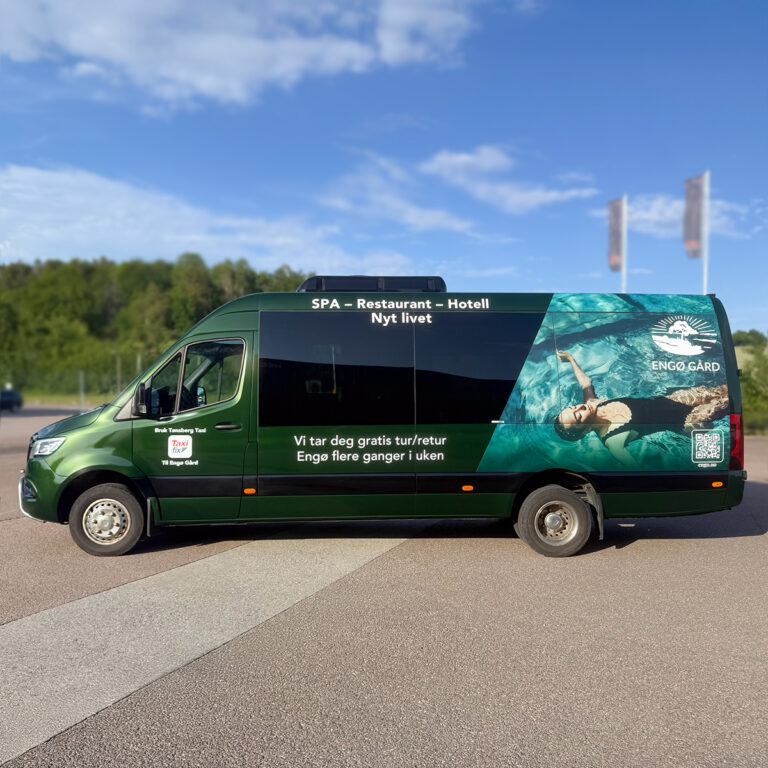 Maxi Taxi sett fra siden med bilreklame for Engø Gård. Helfoliert i britisk racing-grønn og bilde av en kvinne i et badebasseng.