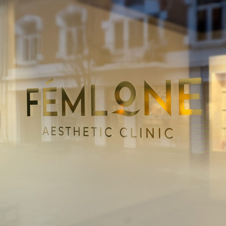 Nærbilde av frostet glass med utskåret gullfolie for Femlone Aesthetic Clinic