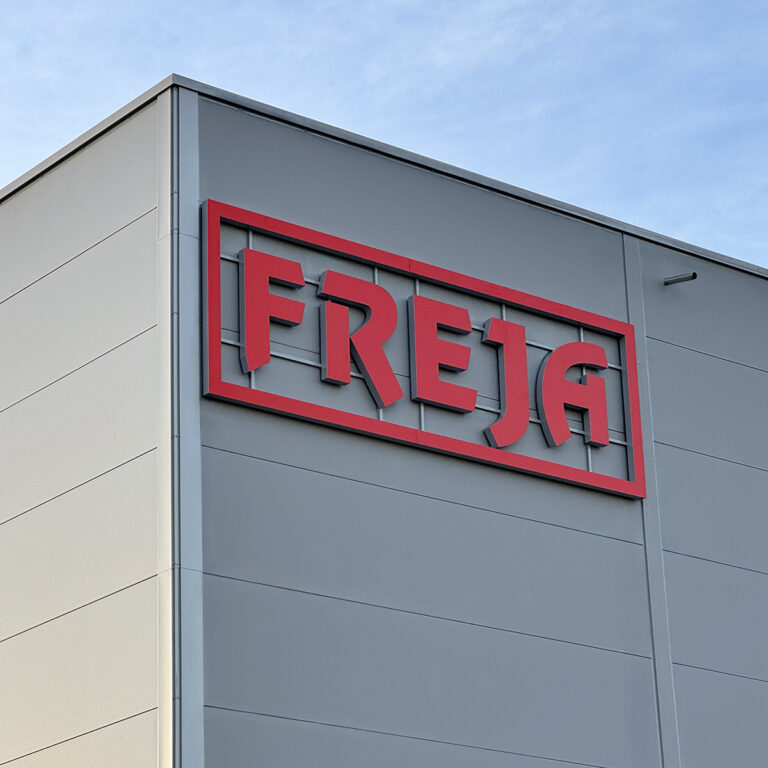 LED-skilt, lysskilt på utvendig fasade. Rød Freja logo på grå bakgrunn