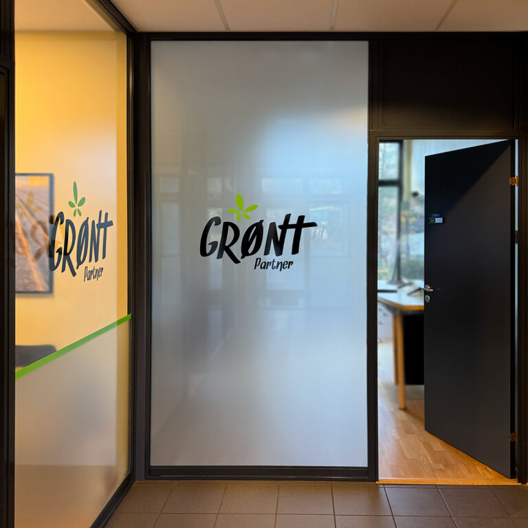 Frostet folie og utskåret folie på glass inn til kontor. Logo Grønt Partner i sort med grønne detaljer.