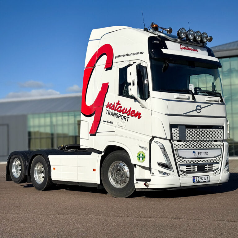 Hvit Volvo lastebil der førerhuset er foliert med rød stor logo for Gustavsen Transport