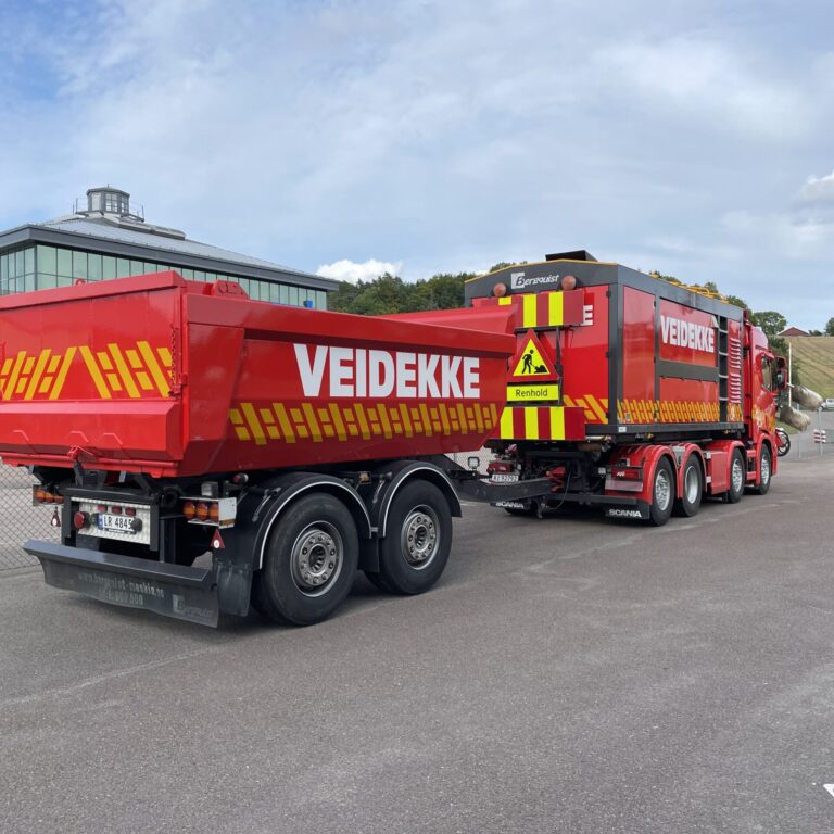 Stor, rød lastebil med henger foliert for Veidekke - lastebildekor sett bakfra