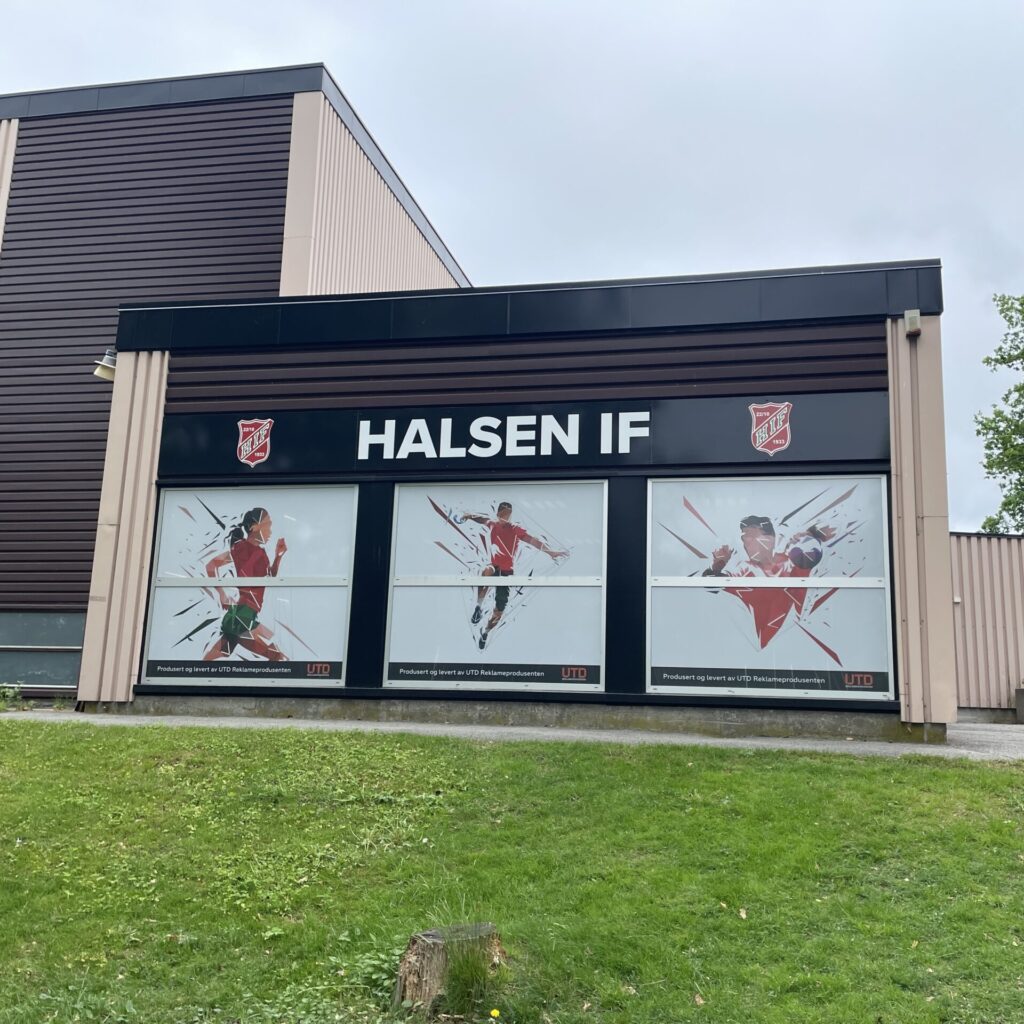 Plateskilt Halsen IF på Bergslihallen med folierte vinduer av håndballspillere