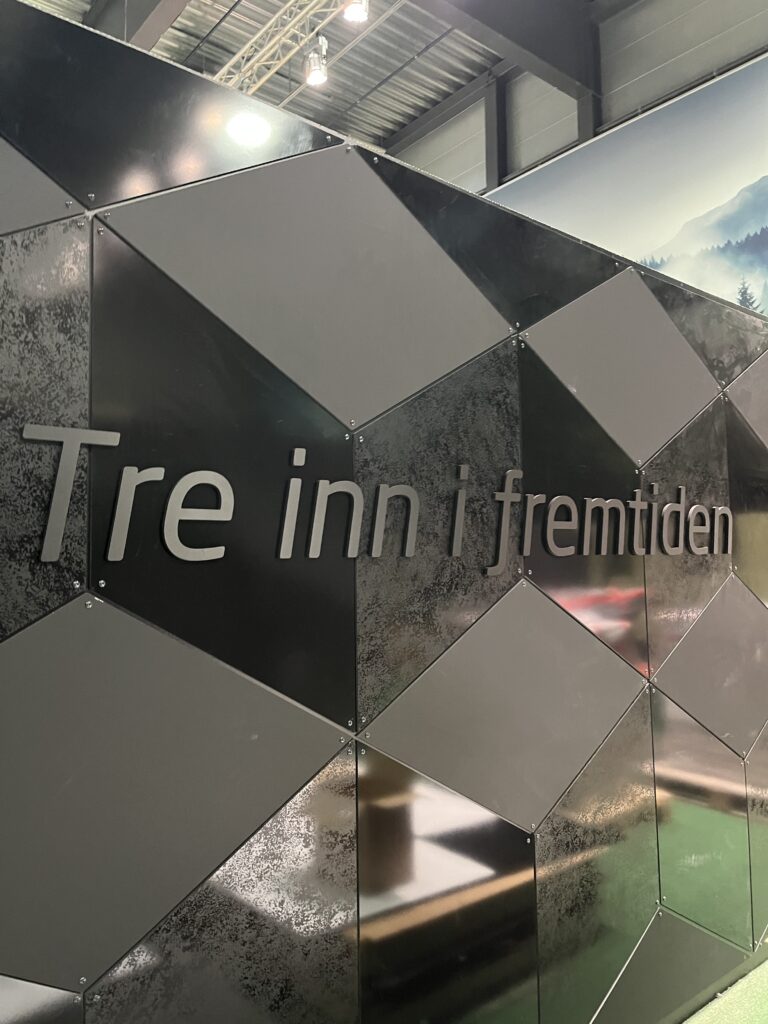 Utstillingsveggen med teksten "Tre inn i fremtiden" på geometriske paneler med naturbilder