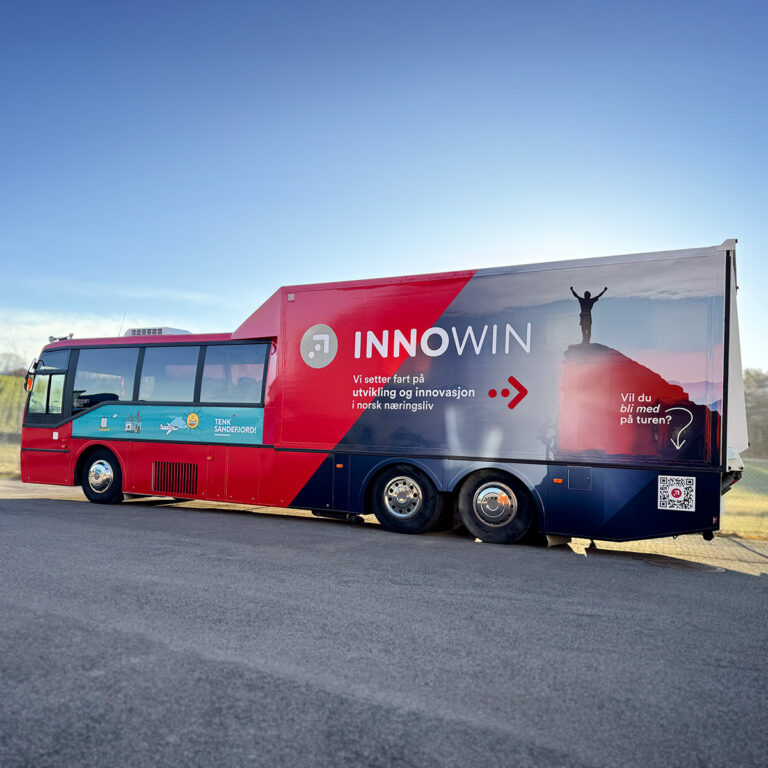Stor helfoliert turnebuss sett fra siden med budskap og foliert logo for Innowin og Tenk Sandefjord