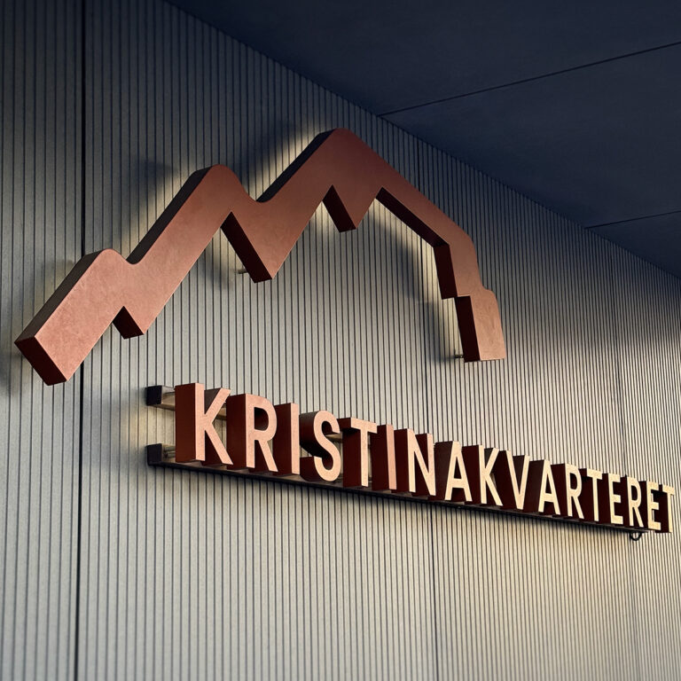 Nærbilde av LED-skilt med bakbelyste bokstaver på utvendig fasade. Logo til Kristinakvarteret