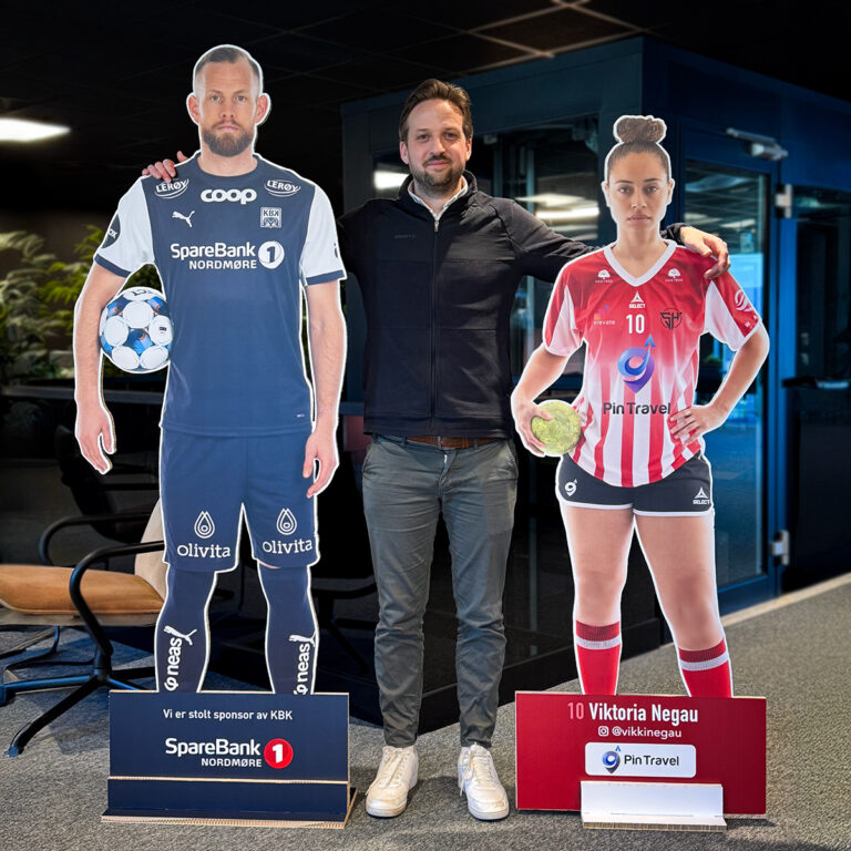 Selger Daniel fra UTD Reklameprodusenten står mellom to helfigurer i utfrest ReBoard. Figurene er en kvinnelig håndballspiller med rød drakt og en mannlig fotballspiller i blå drakt