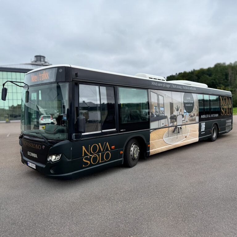 Helfoliert sort buss sett skrått forfra. Bussreklamen har budskap fra Novasolo møbler & interiør