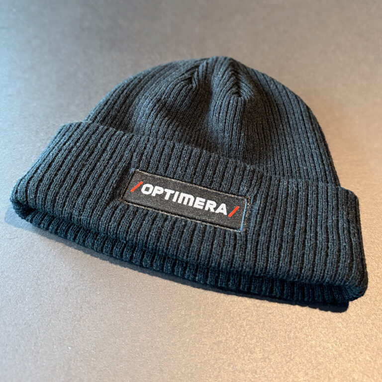 Sort lue i ribbestrikk med påsydd label - Optimera