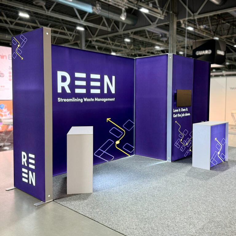 Messestand for Reen med lyskasser i aluminium og tekstilduker med trykk. Messebord med lys på grått teppe