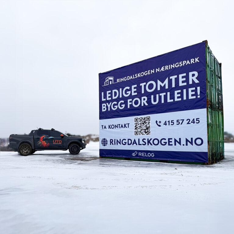 Stort banner i blått og hvitt for Ringdalskogen Næringspark montert på to containere. UTD Reklameprodusenten Pickup til venstre i bildet