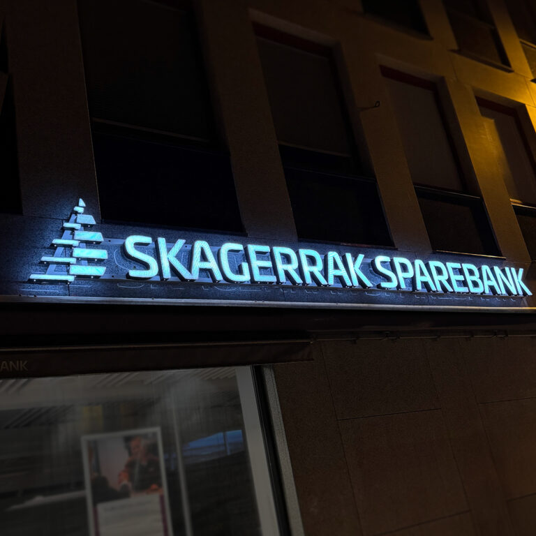 Nærbilde av LED-skilt utvendig for Skagerrak Sparebank på kveldstid med lys