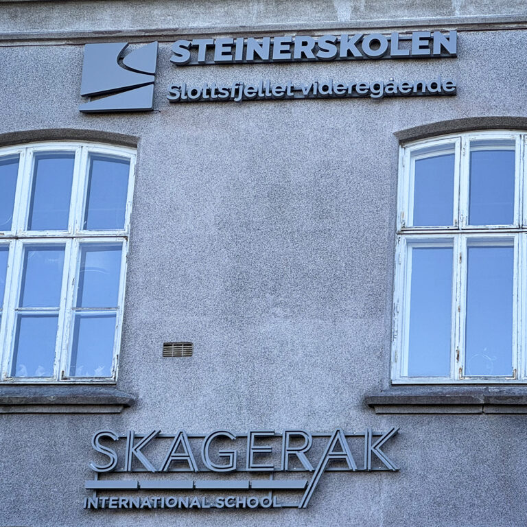 Nærbilde av to LED-skilt på gammel fasade. Steinerskolen Slottfjellet Videregående og Skagerak International School