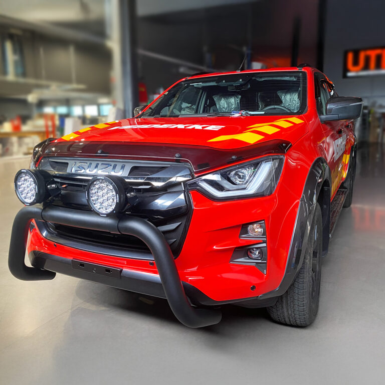 Isuzu pickup sett forfra inne i monteringshallen hos UTD Reklameprodusenten. Bilen er helfoliert rød for Veidekke med logo og gule detaljer
