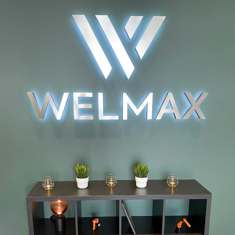 Innvendig lysskilt på grønn vegg. Aluminiumsfinish med bakbelyste bokstaver - logo Welmax