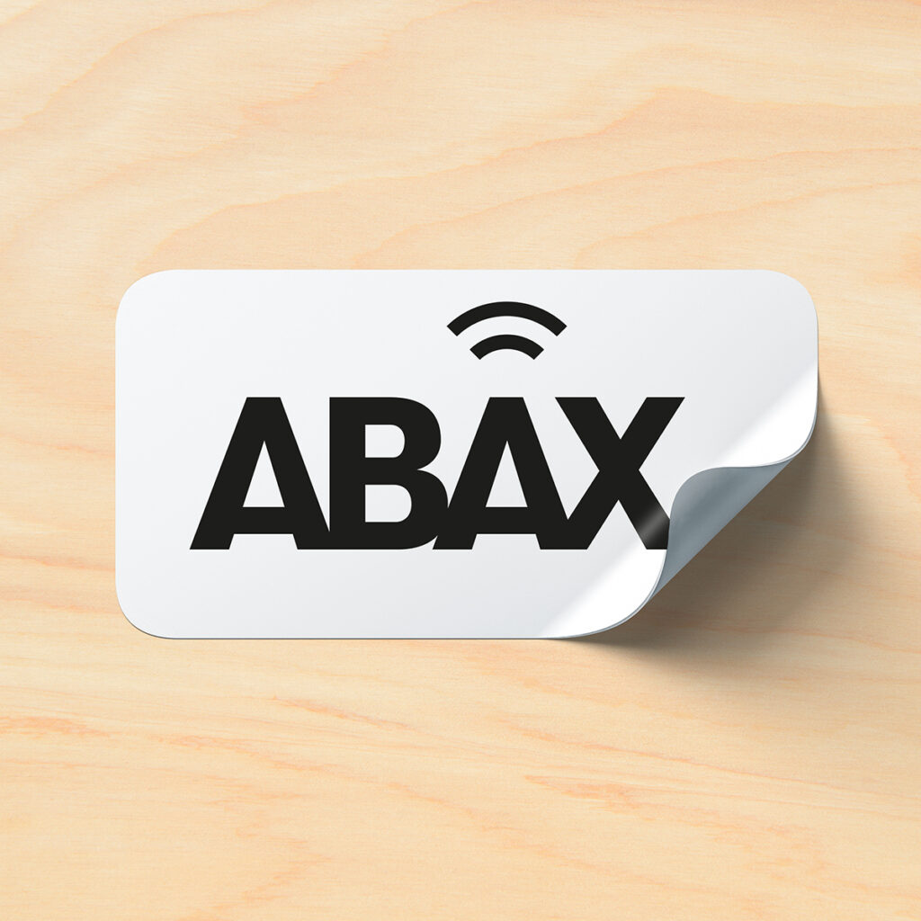 Hvitt klistremerke med Abax logo på trestruktur bakgrunn