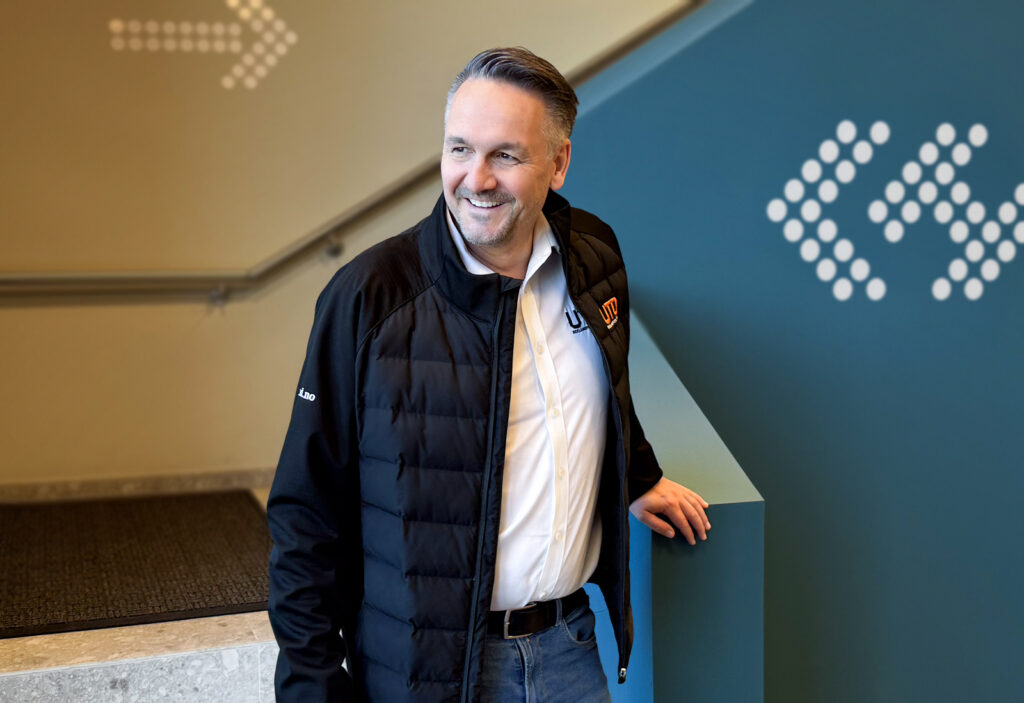 Smilende mann i hvit skjorte og sort profiljakke på befaring ute hos prosjektkunde Larvik Havn