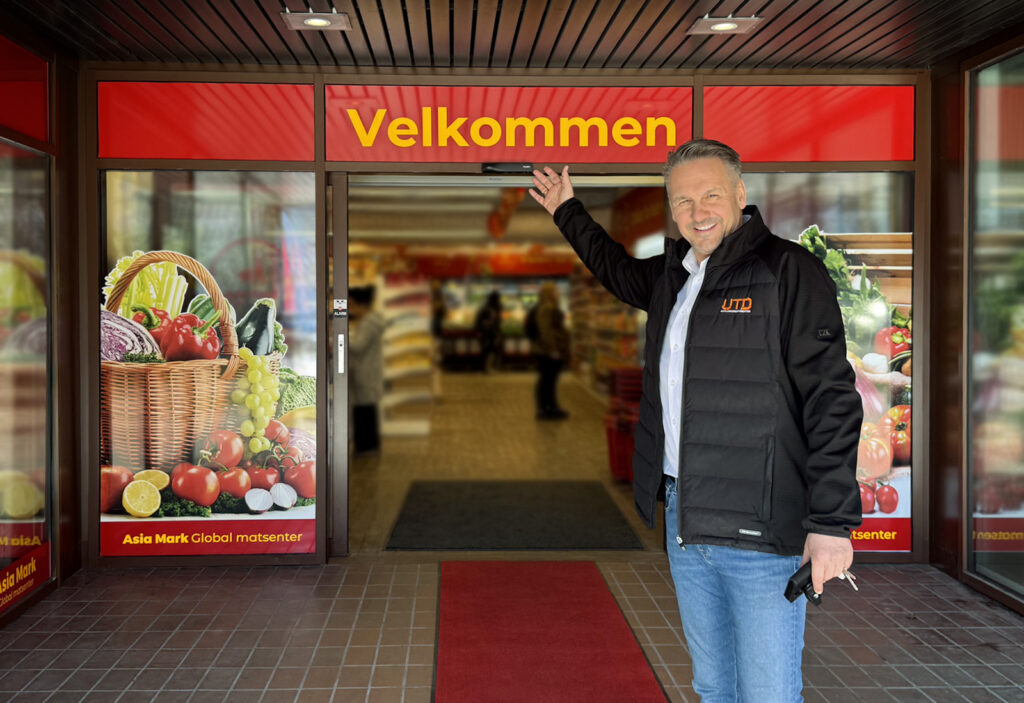 Mann med hvit skjorte og profilert sort jakke foran inngangen til Asiamark