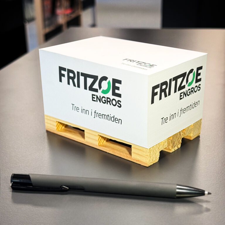 Notatblokk til kontor på liten pall med logotrykk og en reklamepenn. Logo Fritzøe Engros