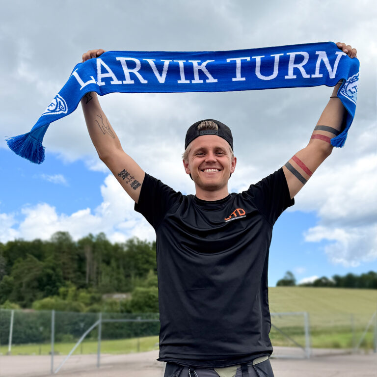 Mann med caps som holder et blått supporterskjerf for Larvik Turn