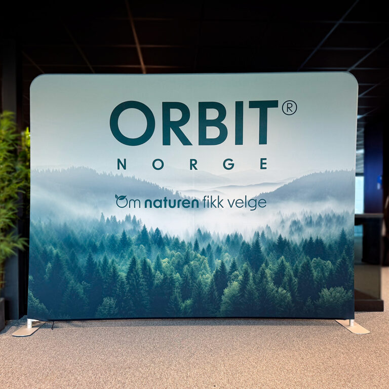 Nærbilde av stor messevegg for Orbit Norge. Aluminiumsramme med tekstilduk trukket rundt. Motiv tåkelagt skogsområde med logo