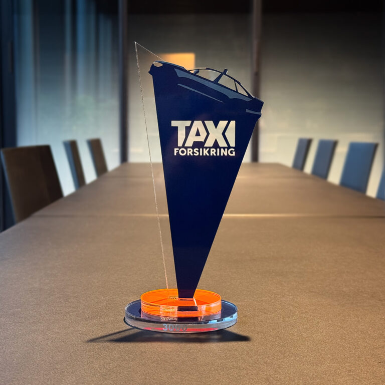 Spesiallaget pokal i akryl med folie for Fair Insurance. Pokalen står på et sort konferansebord hos UTD Reklameprodusenten