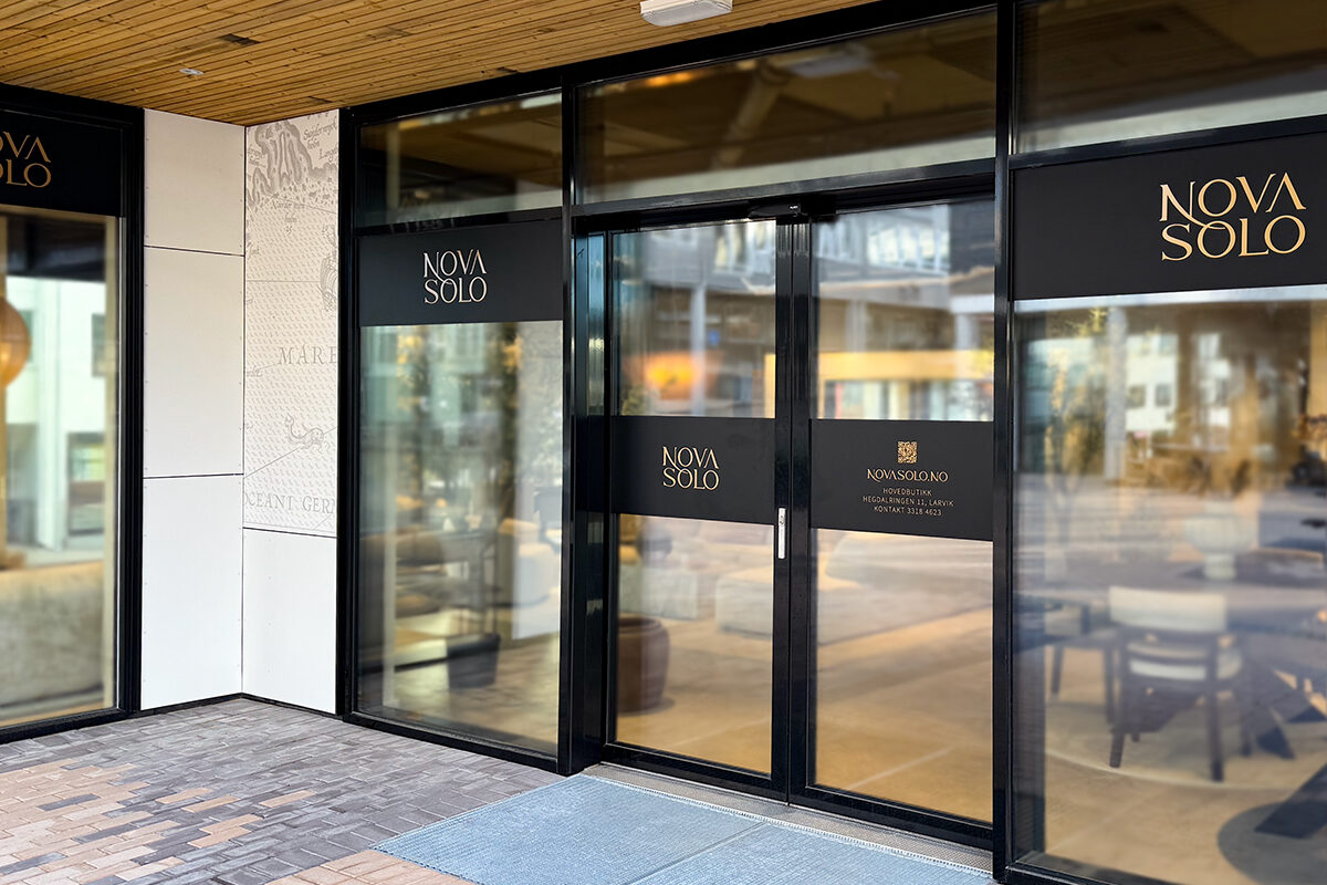 Inngangsparti med skyvedører og glassfelt til showroom for Novasolo. Sort folie med gullprint