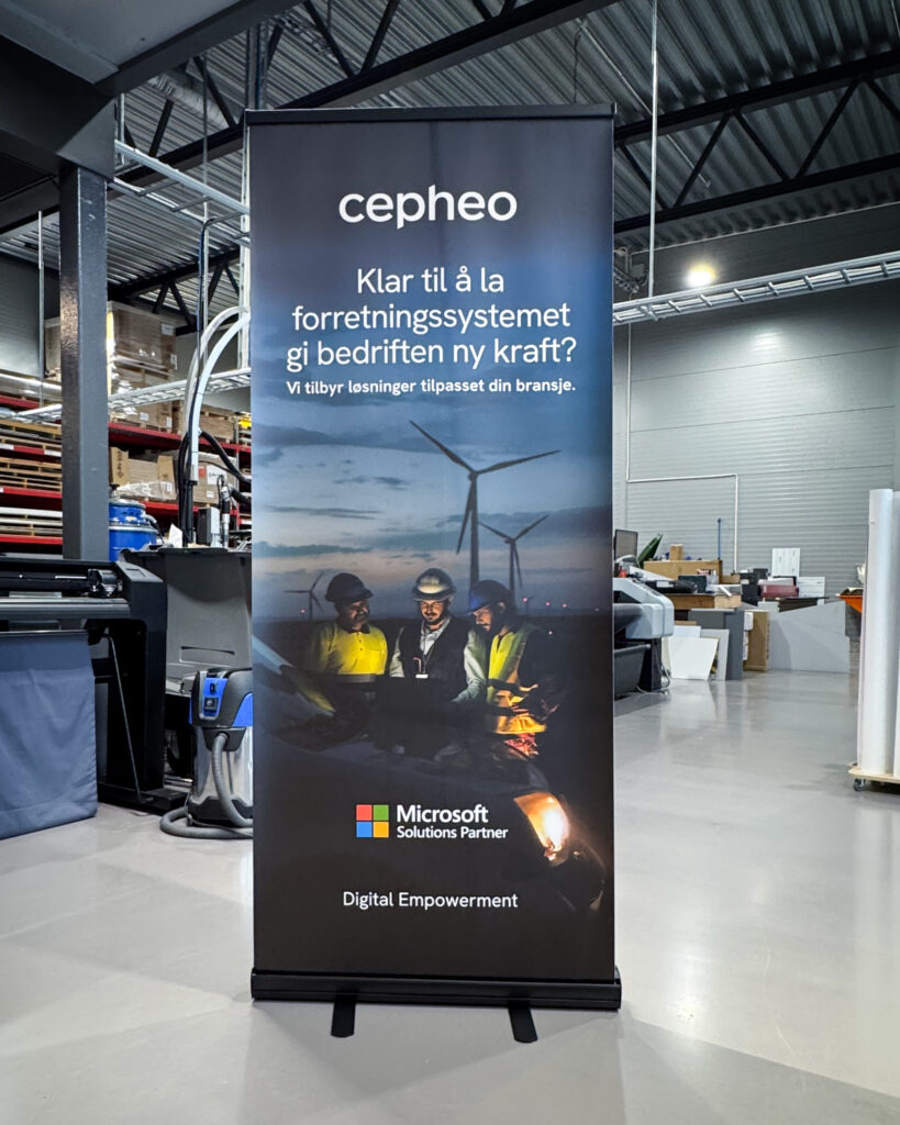 Cepheo-banner (roll-up) med tekst om forretningssystem for bedrifter, Microsoft Solutions Partner-logo, og bilde av tre arbeidere med vindmøller i bakgrunnen