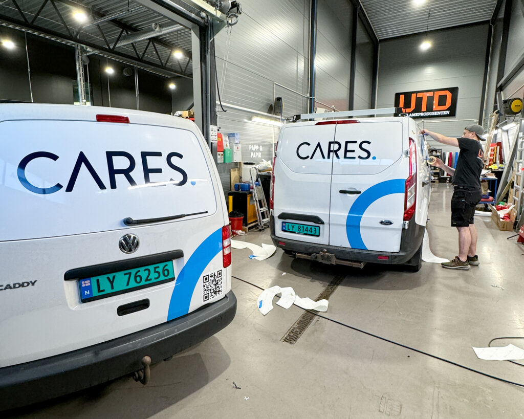 Foliemontør som monterer folie og logo på varebiler inne i monteringshall hos UTD Reklameprodusenten for Cares AS.