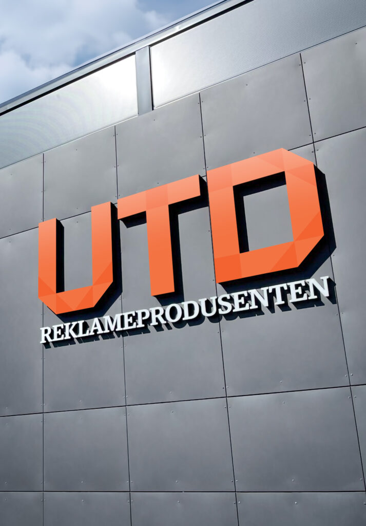 Oransje logo med teksten "REKLAMEPRODUSENTEN" på grå bygningsfasade