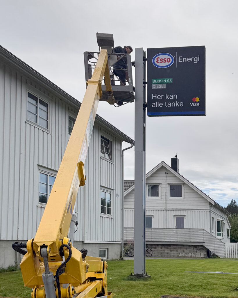UTD-montør i lift monterer Esso Energi veggskiltt med informasjonstavle – montering av LED-skilt på høyde